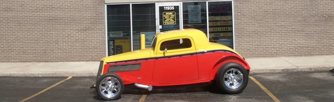 A yellow and red car parked in front of a building.